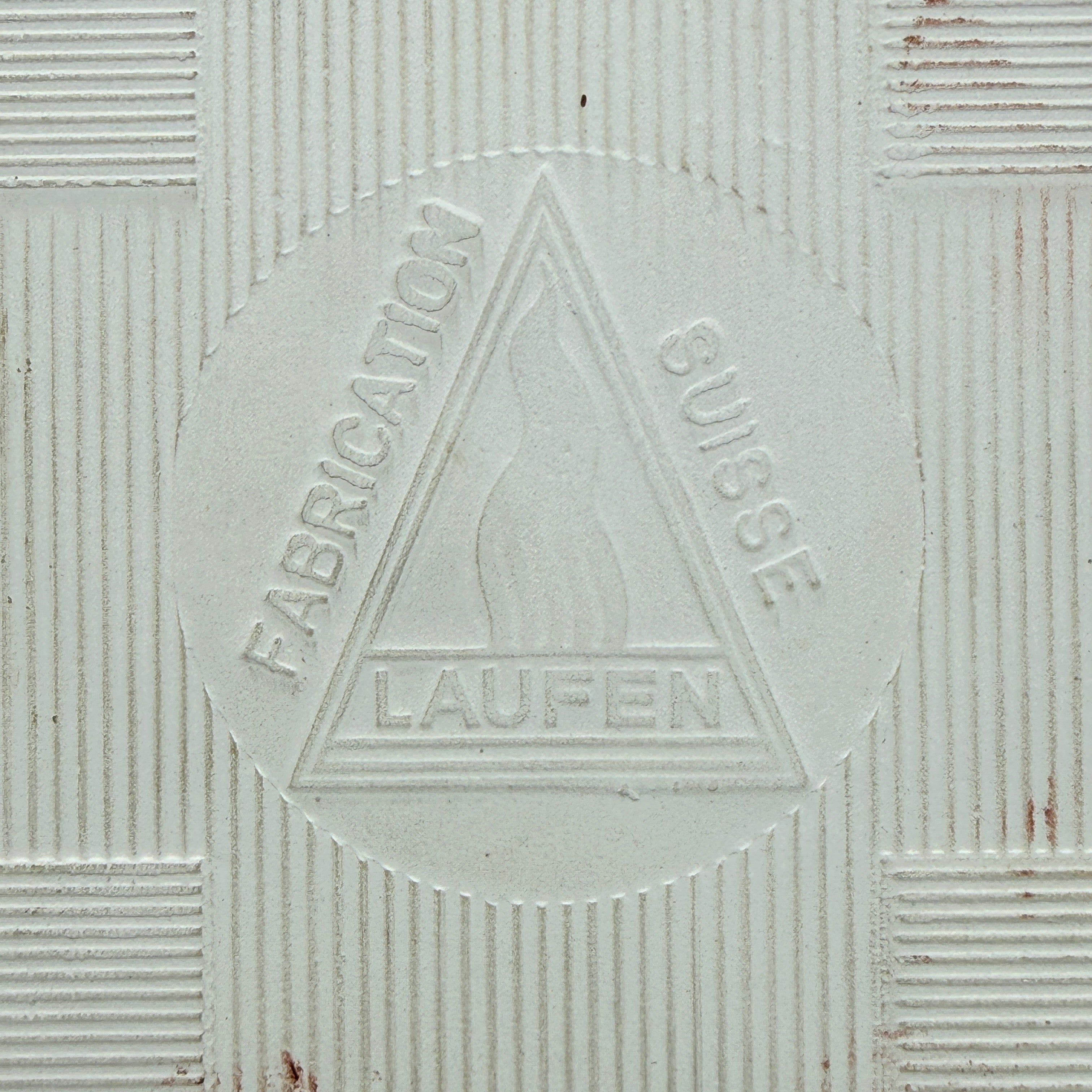 Showroom Ansbach Keramikfliese mit eingeprägtem Laufen Fabrication Suisse Logo auf cremeweißer, texturierter Oberfläche