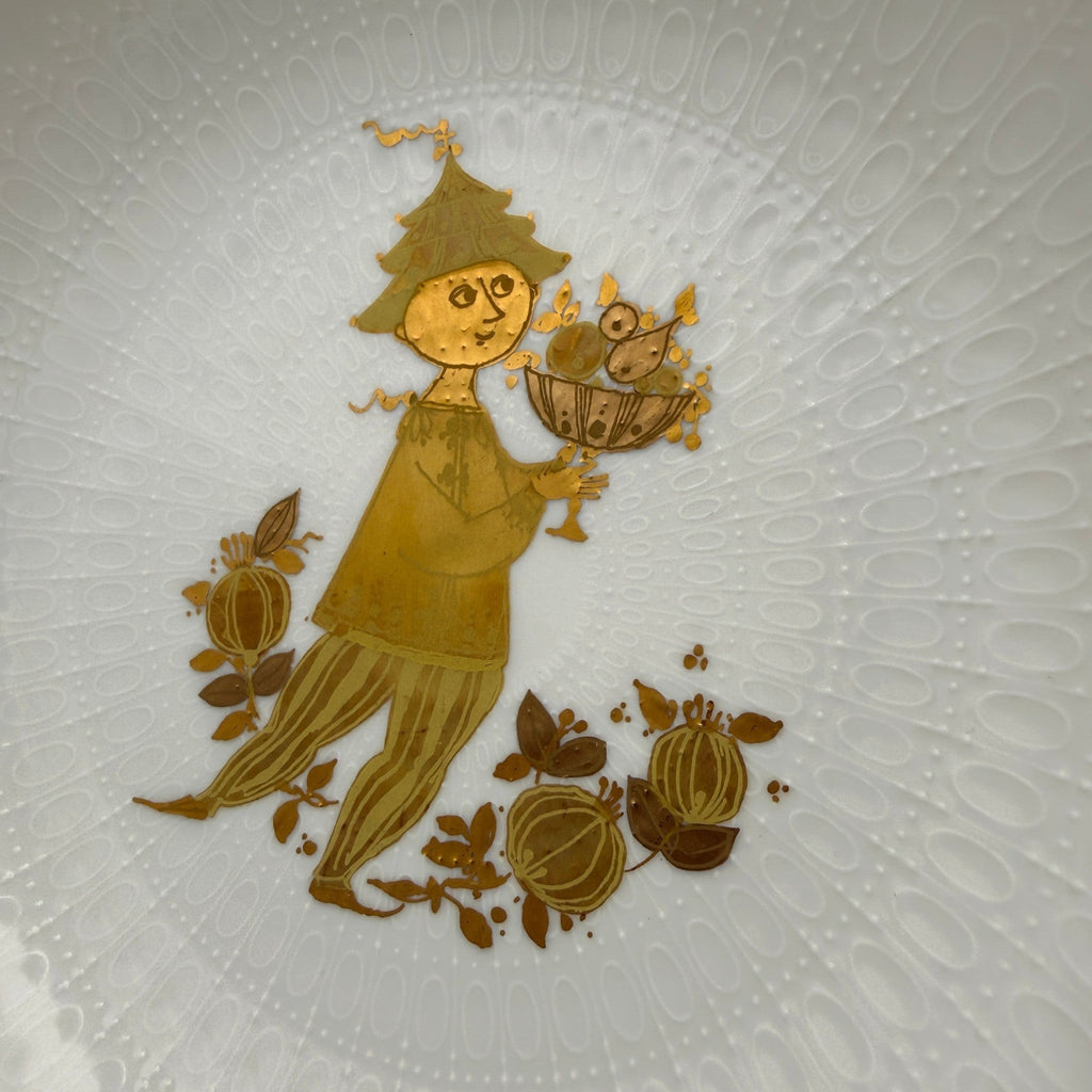 Showroom Ansbach weißer Porzellanteller mit geprägter Textur und goldener Illustration einer märchenhaften Figur