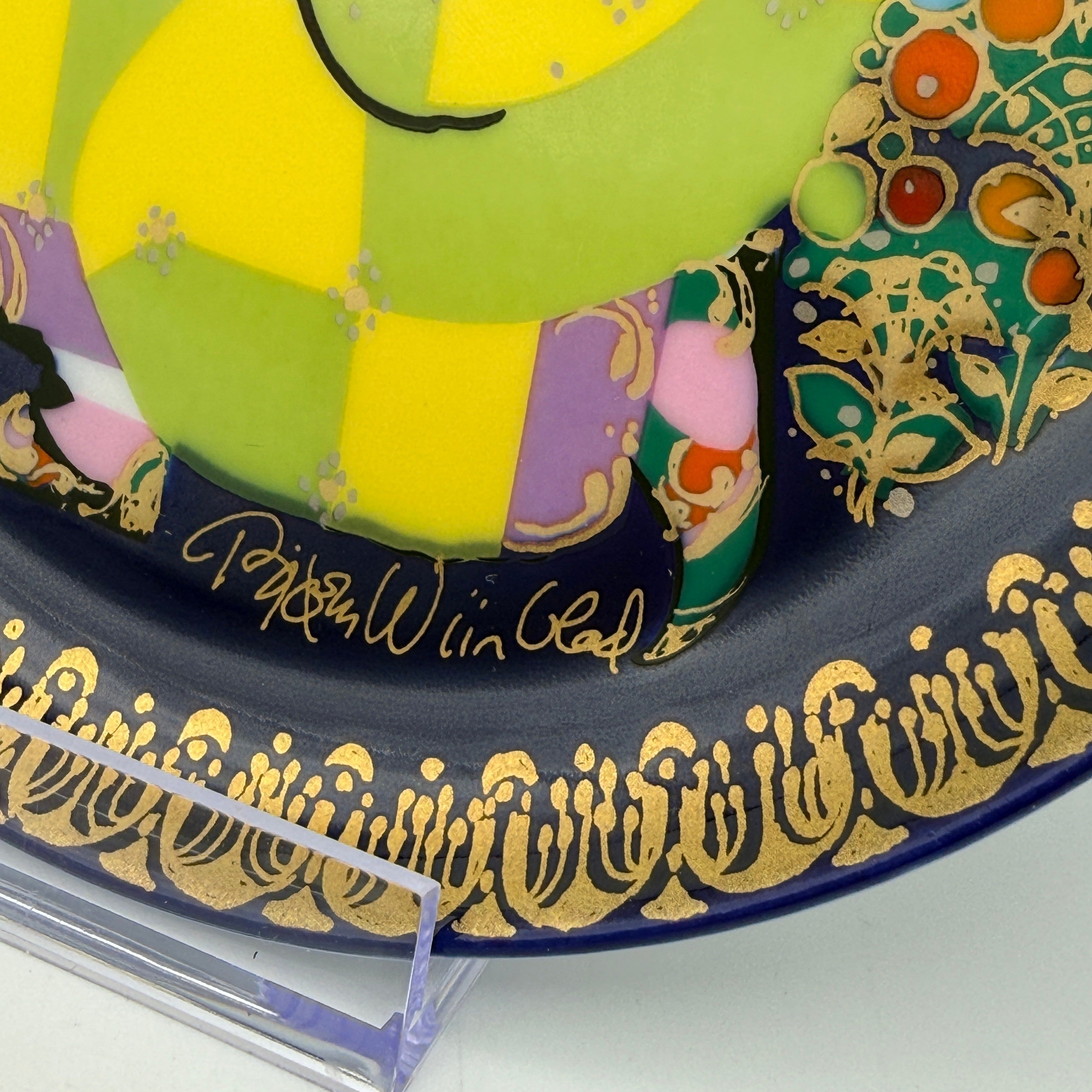 Showroom Ansbach Porzellanteller mit buntem, figurativem Motiv, tiefblauem Hintergrund und luxuriöser Goldbordüre.