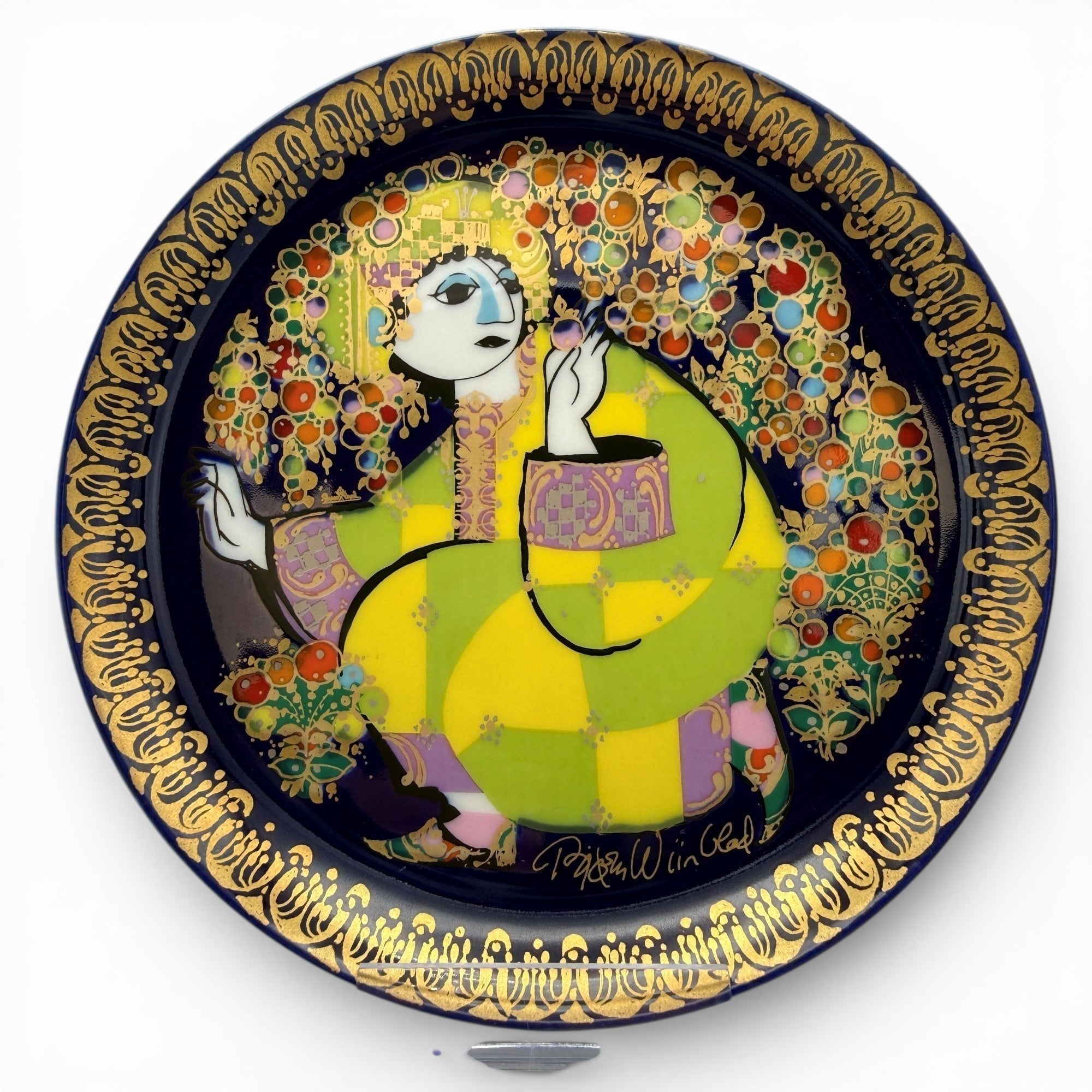 Showroom Ansbach Zierteller aus Porzellan mit stilisierter Figur in Gelb und Grün auf Blau mit goldener Bordüre