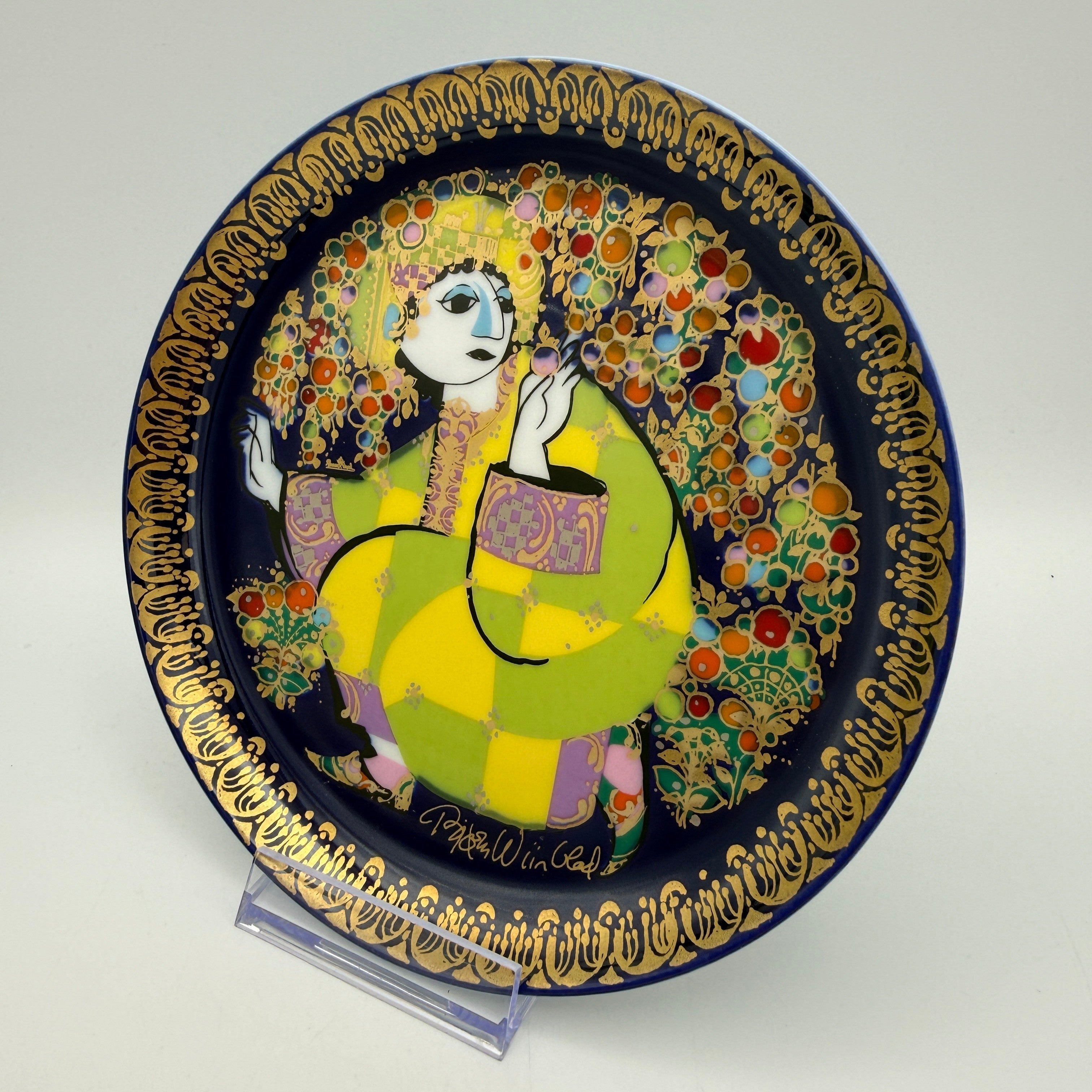 Showroom Ansbach Porzellanteller mit stilisierter Figur in Gelb und Grün auf Blau mit goldener Bordüre