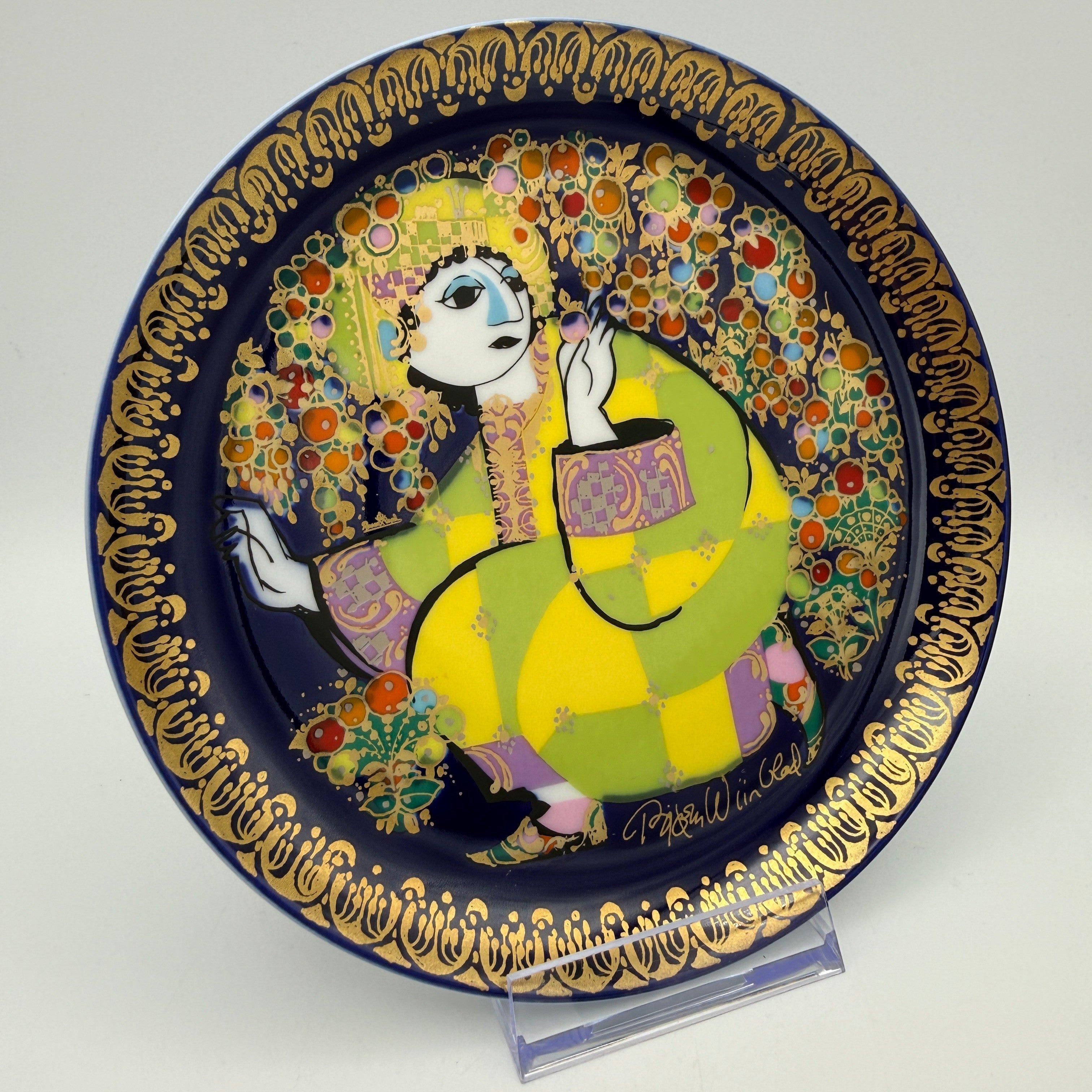 Showroom Ansbach dekorativer Porzellanteller mit stilisierter Figur in Gelb und Grün auf Blau mit Goldrand
