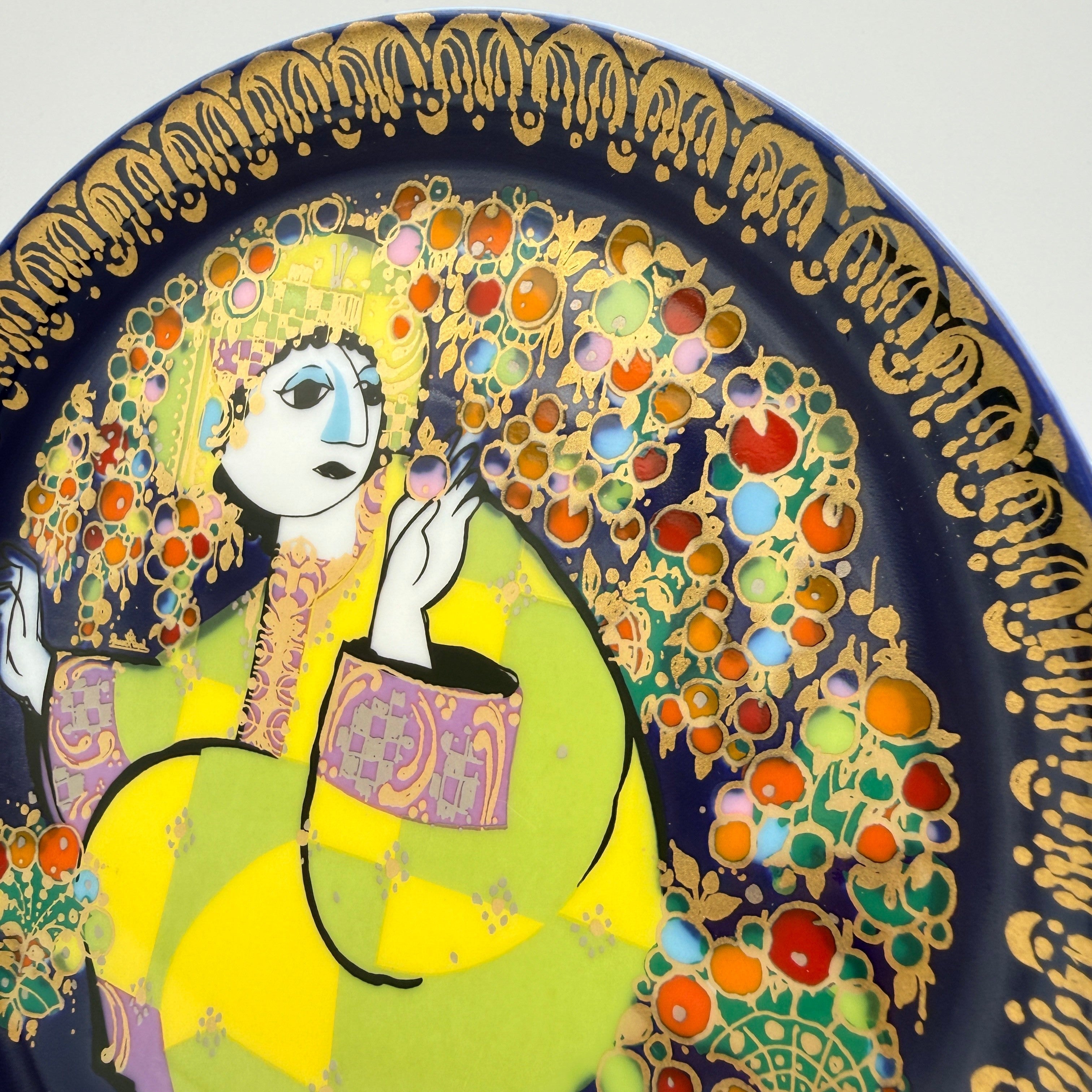 Showroom Ansbach Porzellanteller mit stilisierter Figur in Gelb und Grün auf tiefblauem Grund mit goldener Bordüre